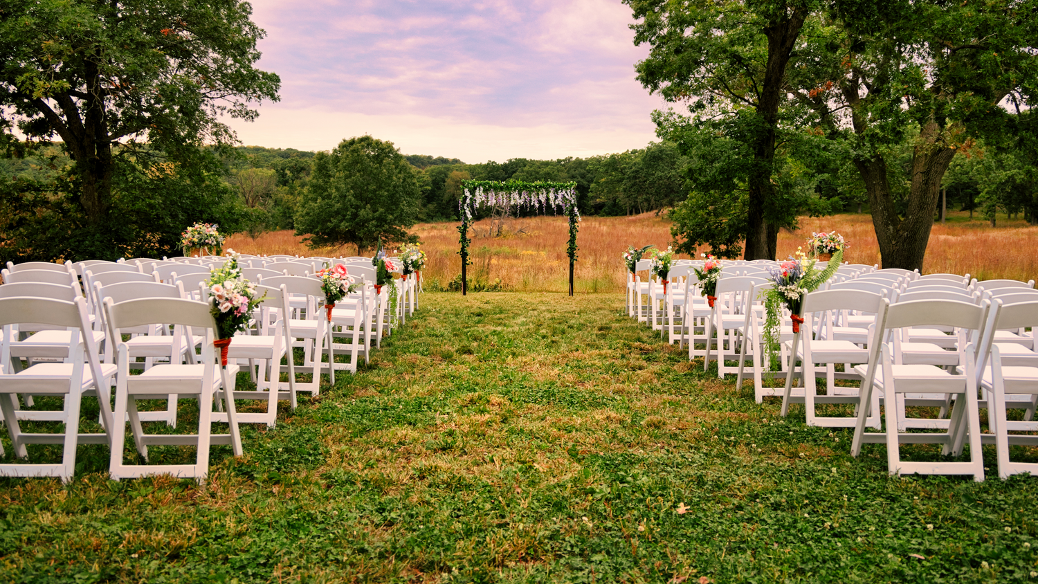Outdoor wedding setup with white chairs and floral arrangements on TWR's Prairie.